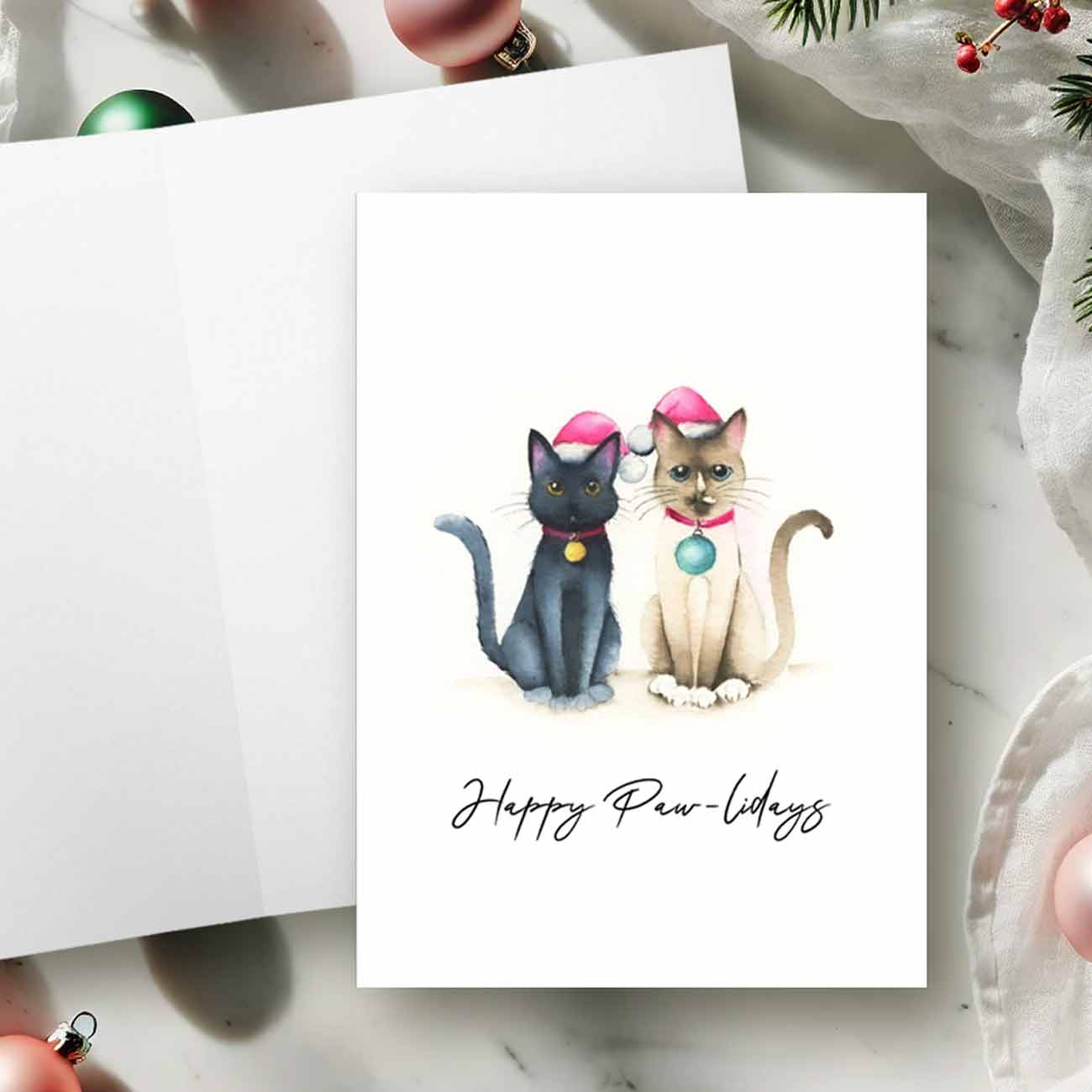 Cat Christmas cards by Victoria Grigaliunas of Do Tell A Belle featuring a watercolor painting of a Siamese cat and a black cat, on the card front with the words "Happy Paw-lidays". Blank inside, perfect for holiday greetings and a thoughtful way to support small business Saturdays.