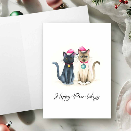 Cat Christmas cards by Victoria Grigaliunas of Do Tell A Belle featuring a watercolor painting of a Siamese cat and a black cat, on the card front with the words "Happy Paw-lidays". Blank inside, perfect for holiday greetings and a thoughtful way to support small business Saturdays.