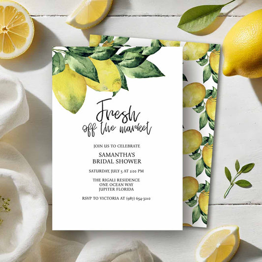 Flat lay of lemon bridal shower invitations with a top boarder of watercolor lemon art by Victoria Grigaliunas of Do Tell A Belle. The back of the card features a matching lemon pattern.