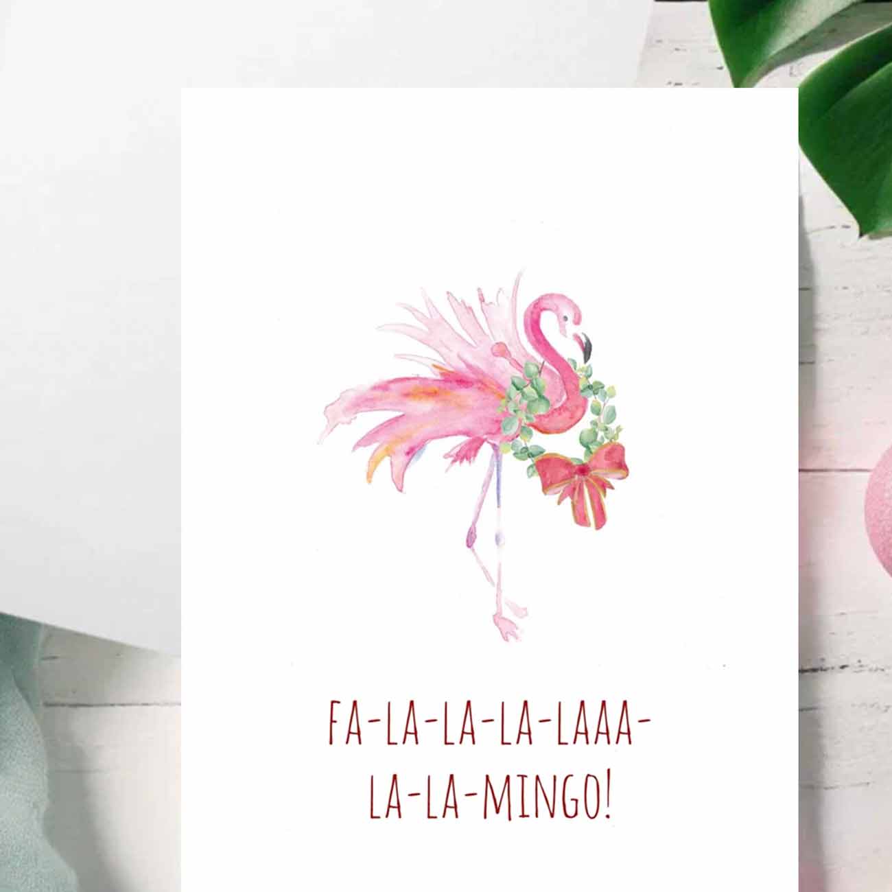 zoomed in flat lay of pink flamingo Christmas cards designed by watercolor artist Victoria Grigaliunas of Do Tell A Belle a woman owned small business in Palm Beach, Florida