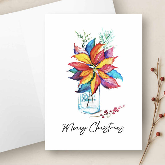 Colorful watercolor poinsettia Christmas card in a rustic canning jar with “Merry Christmas” in script, blank inside for personal messages or holiday cards printable. Design by Do Tell A Belle. Watercolor art by Victoria Grigaliunas