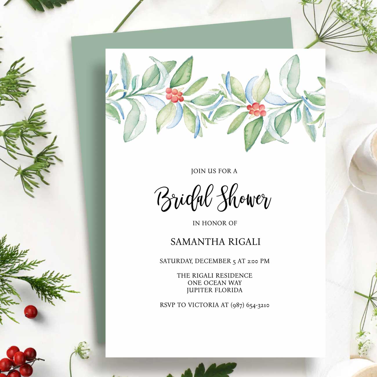 Flat lay of winter bridal shower invitations template designed with water botanical art in shades of red and green on a crisp what background. Art and design by Victoria Grigaliunas of Do Tell A Belle a woman owned small business in Palm Beach Gardens Florida.