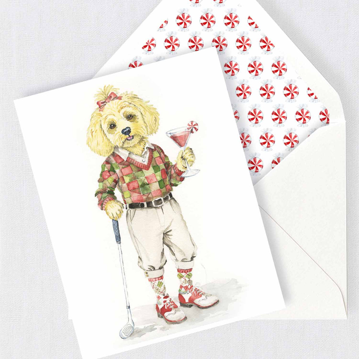 Watercolor Morkie Poo Christmas card wearing a festive golf outfit and holding a peppermint martini with peppermint candy envelope liner.
