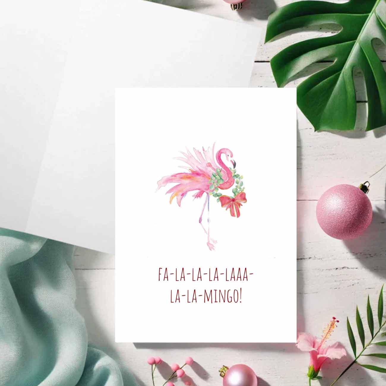 A flat lay of charming pink flamingo Christmas cards designed by watercolor artist Victoria Grigaliunas of Do Tell A Belle a woman owned small business in Palm Beach, Florida