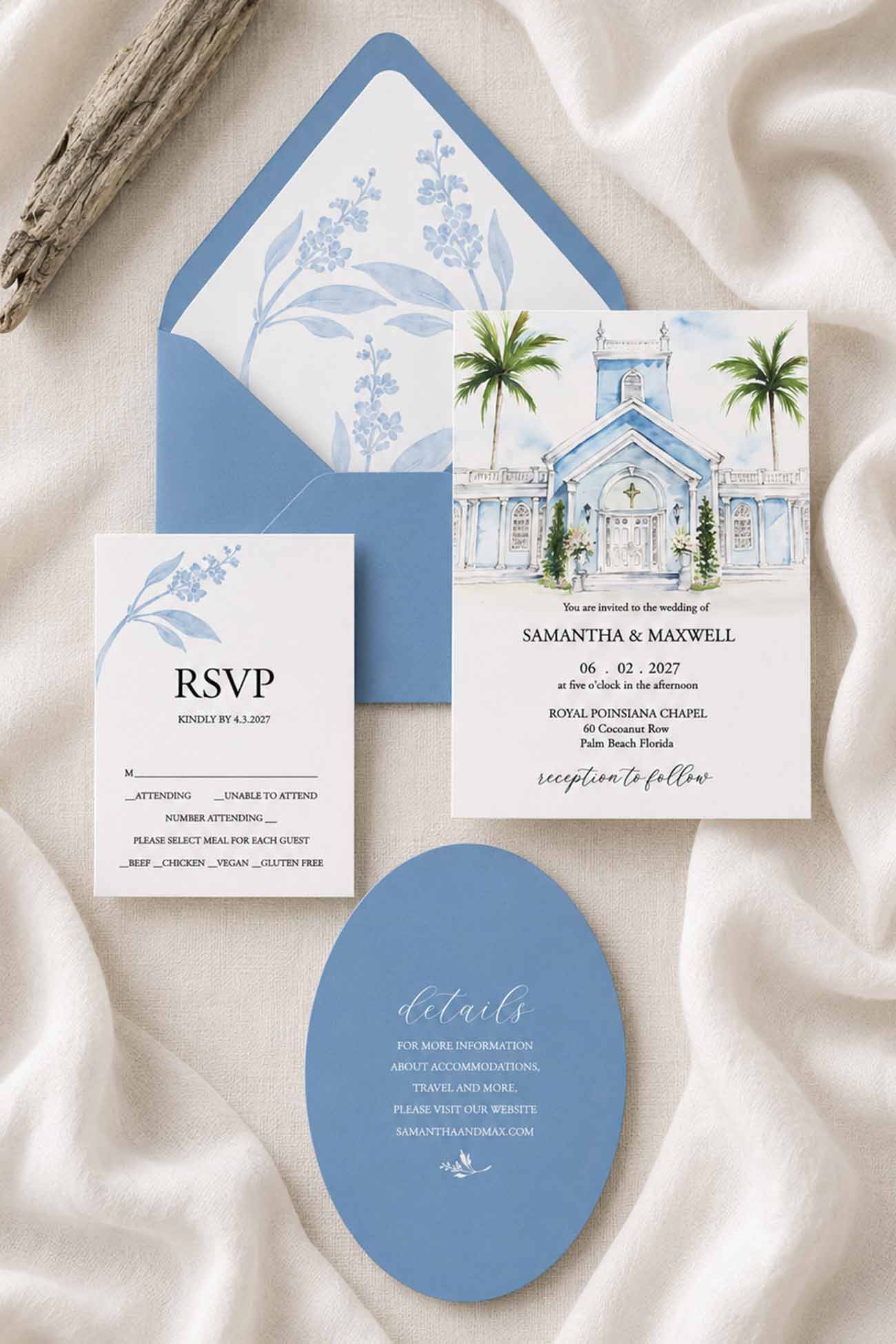 A coordinated wedding stationery set arranged on draped cream fabric, including a watercolor painting of the Royal Poinciana Chapel with palm trees invitation card with blue watercolor envelope, an RSVP card with blue floral print, a die cut blue oval details card, and a wood branch prop.